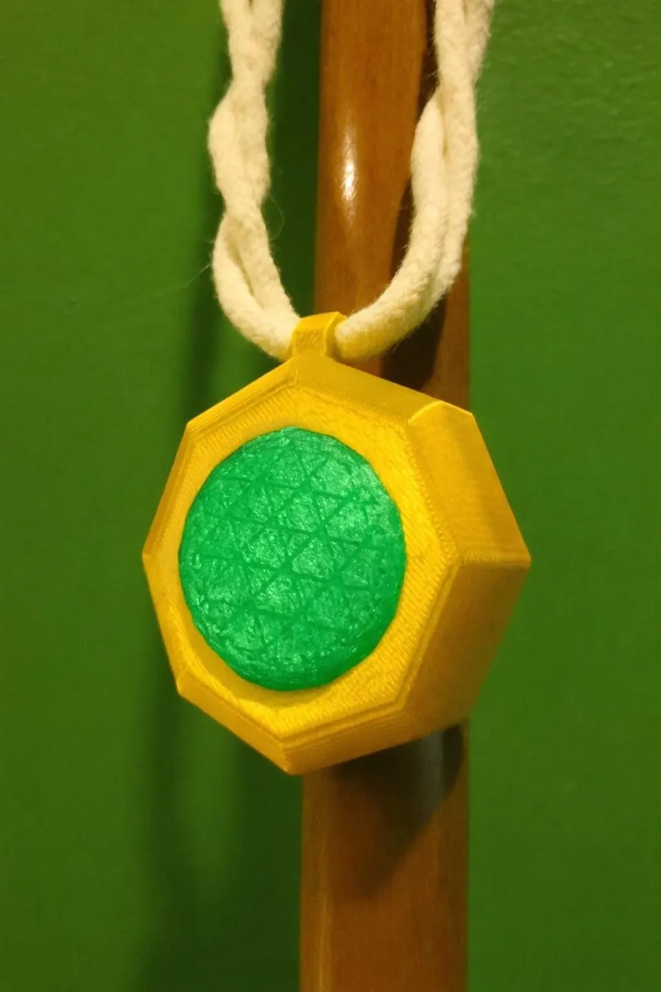 Amulet of defense with a green emerald, hanging from a braided cord